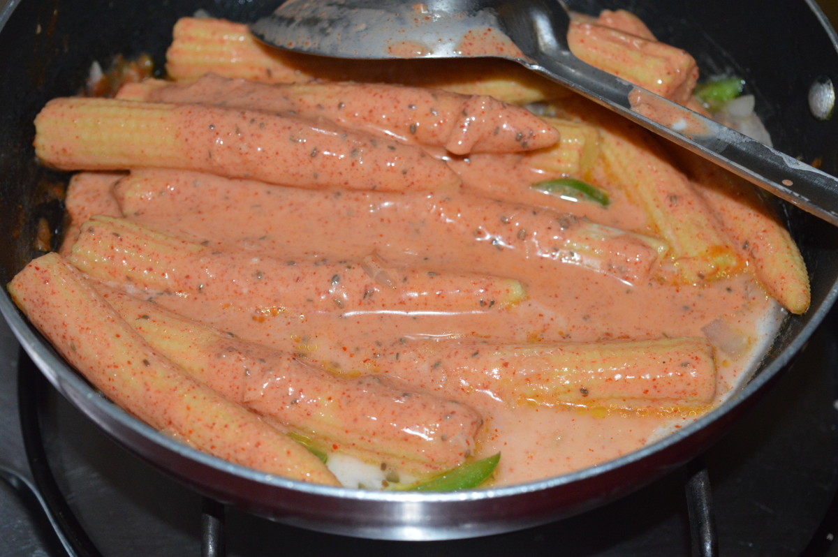 4. Add the marinated baby corn and corn flour mixture. Gently mix with the other content in the pan. Turn off the heat when the baby corn gets coated with the spices and the raw smell of the corn flour disappears. 