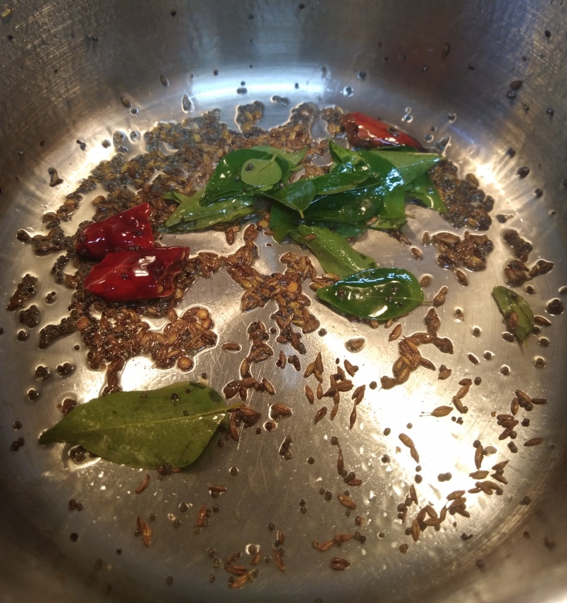 Add mustard and cumin seeds; let them splutter. Add broken red chilies and curry leaves. Fry for a few seconds.