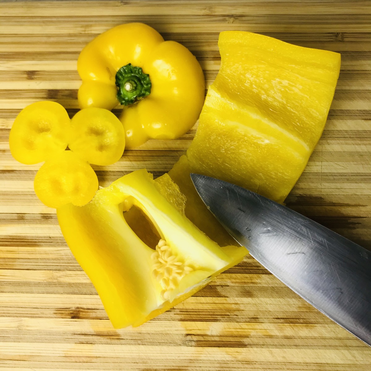 Begin by slicing the top and the bottom off of the pepper. Then, slice through the side, and run your knife along the inside and around the core to remove all the seeds and ribs intact. Thinly slice the pepper, including the top and bottom pieces.
