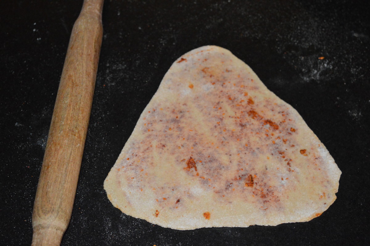 Roll it out to make a big, thin triangle. This is the raw spicy paratha.