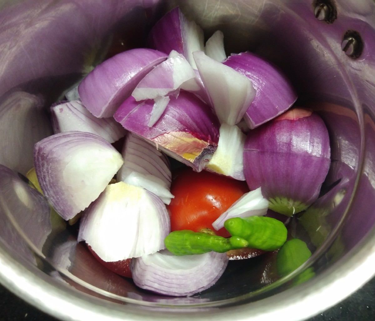 Meanwhile, in a mixer jar, add roughly chopped onion, tomatoes, ginger, garlic, and green chilies. 