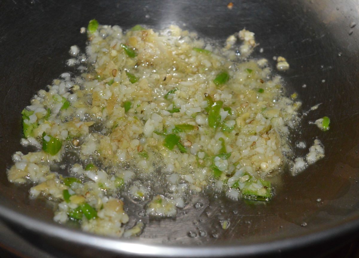 Step three: Heat oil in a deep-bottomed pan. Add chopped garlic, ginger, and green chilies to it. Saute the mixture on high heat for a minute or until the raw smell escapes.  