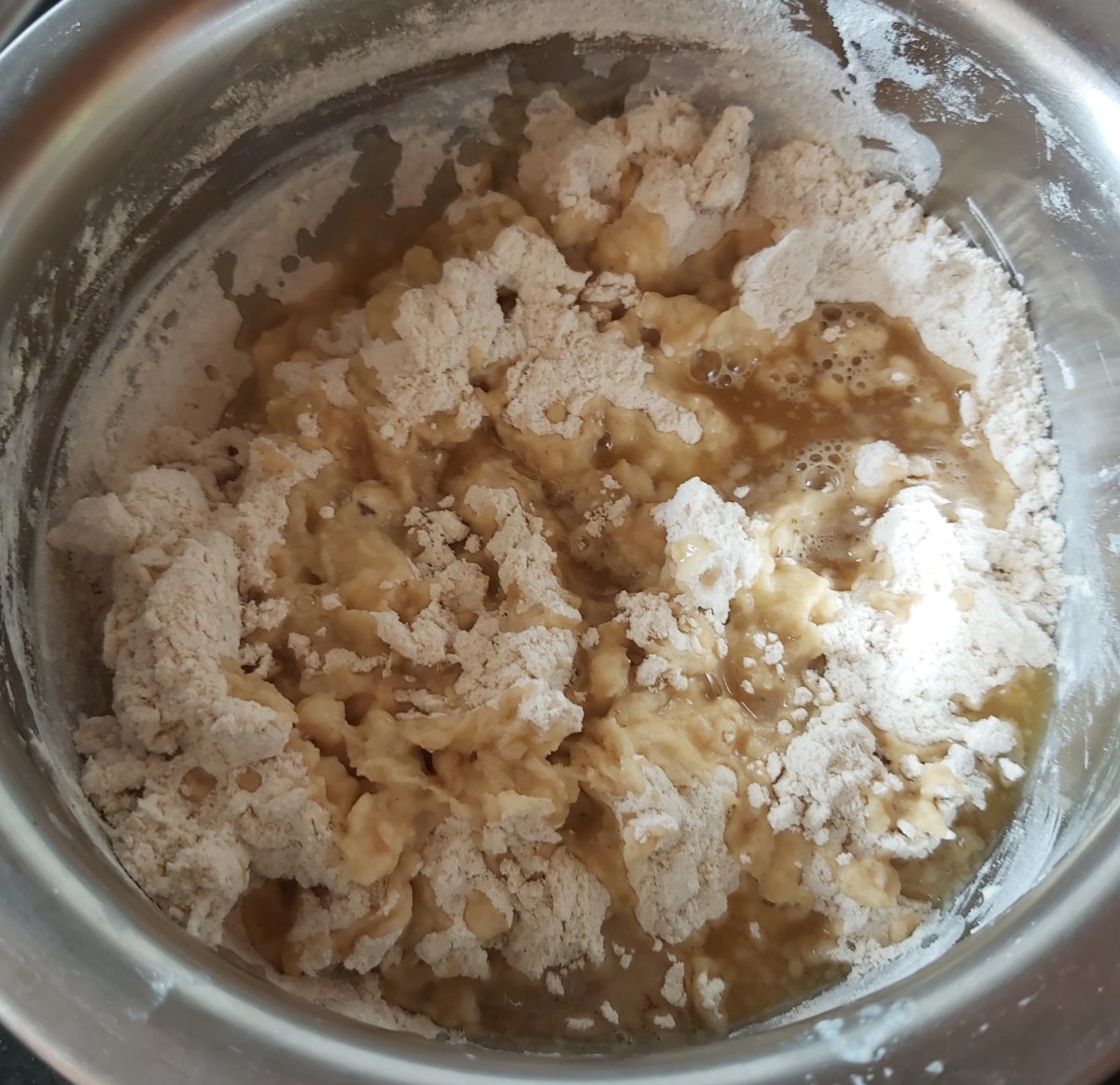 Gradually add jaggery syrup to the flour mixture. Mix well.