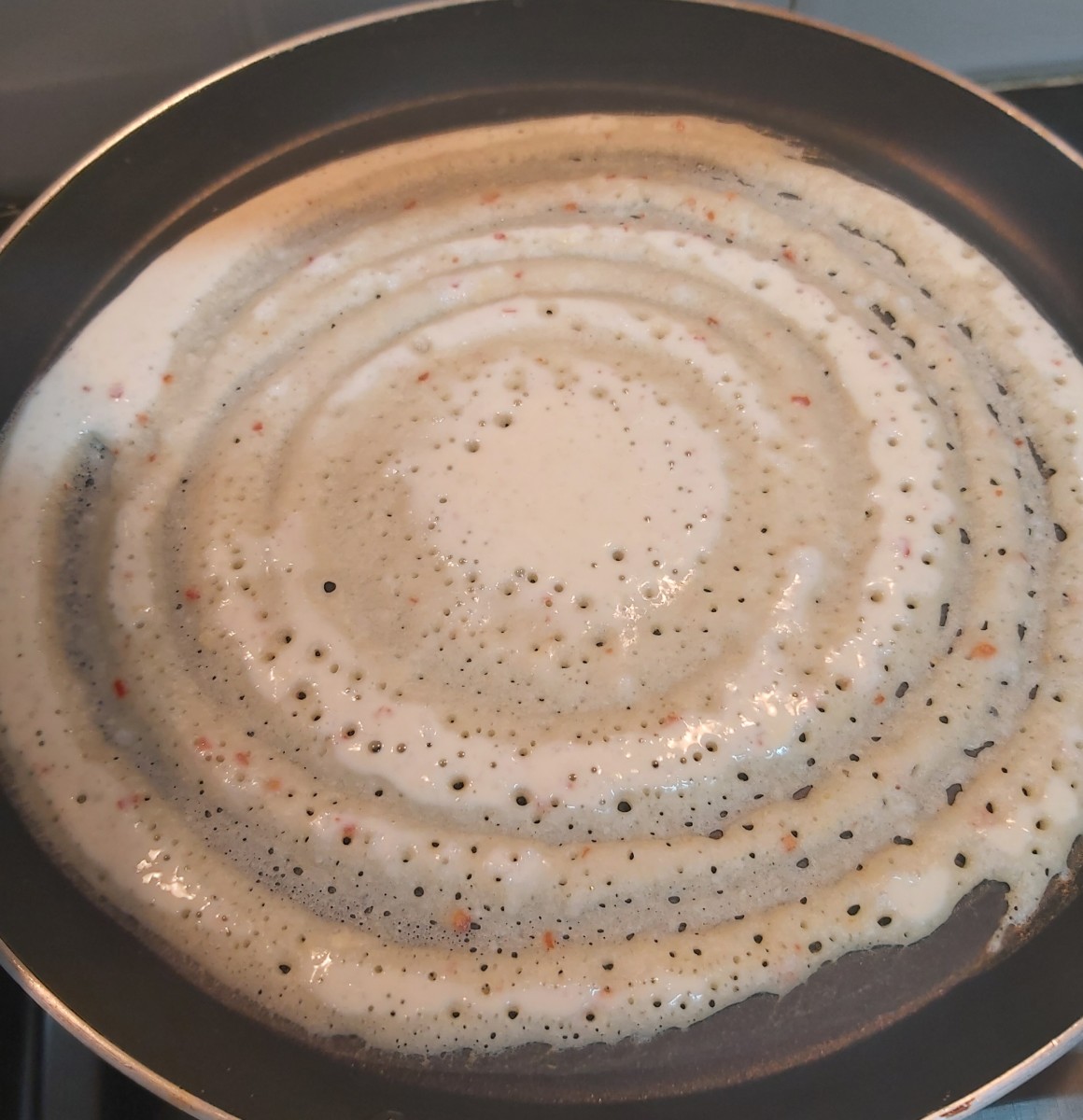 Heat the tawa on high flame. Pour a ladleful of batter on tawa and spread it gently. Sprinkle some drops of oil or ghee on top of dosa (optional).