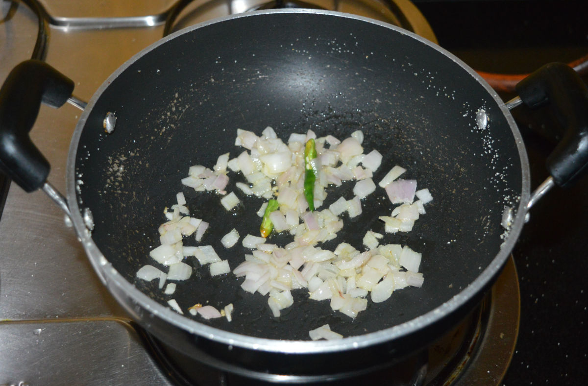 Step 3: In the same deep-bottomed pan, add some oil. Add chopped onions and slit green chilies. Saute until the onions become pinkish.