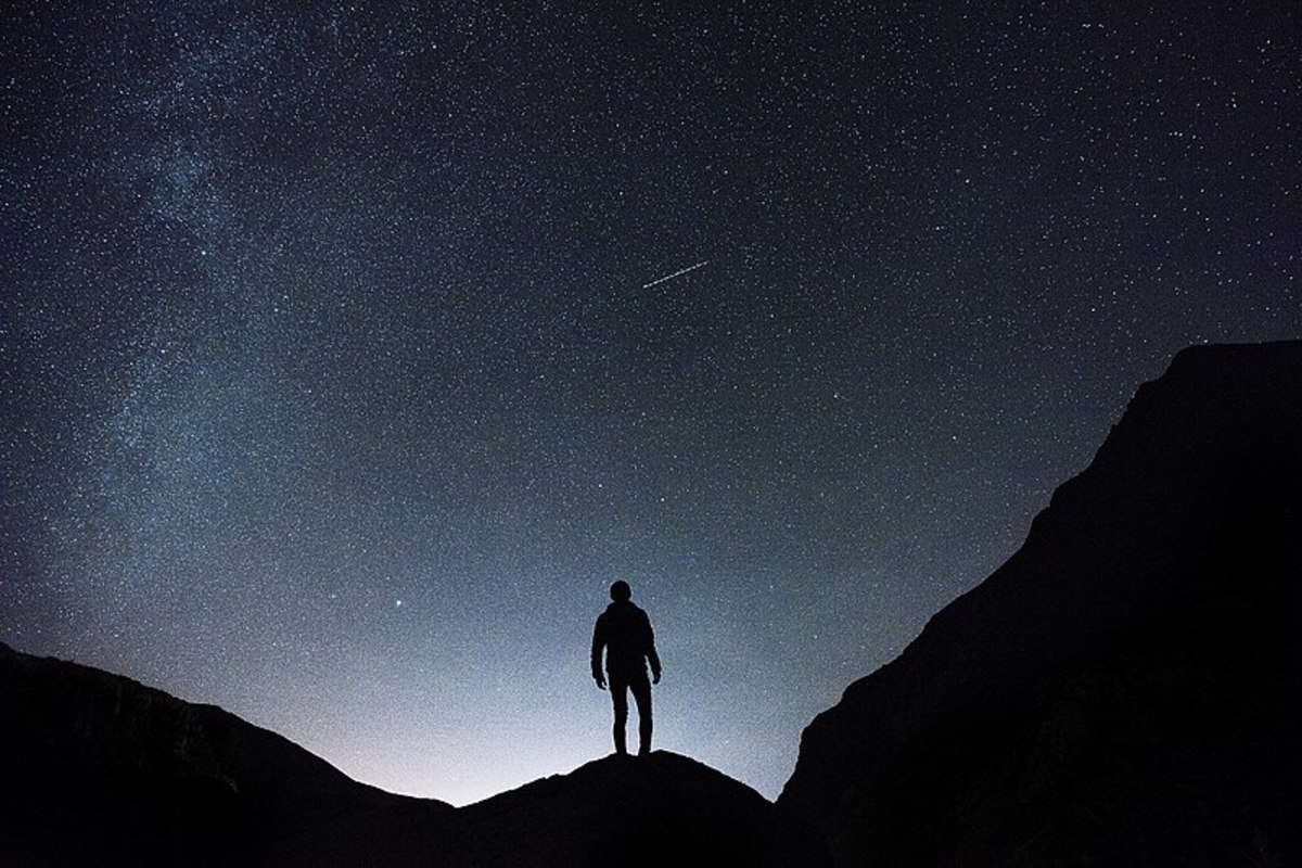 A man stands and observes a sky full of stars above Snowdonia National Park in the United Kingdom