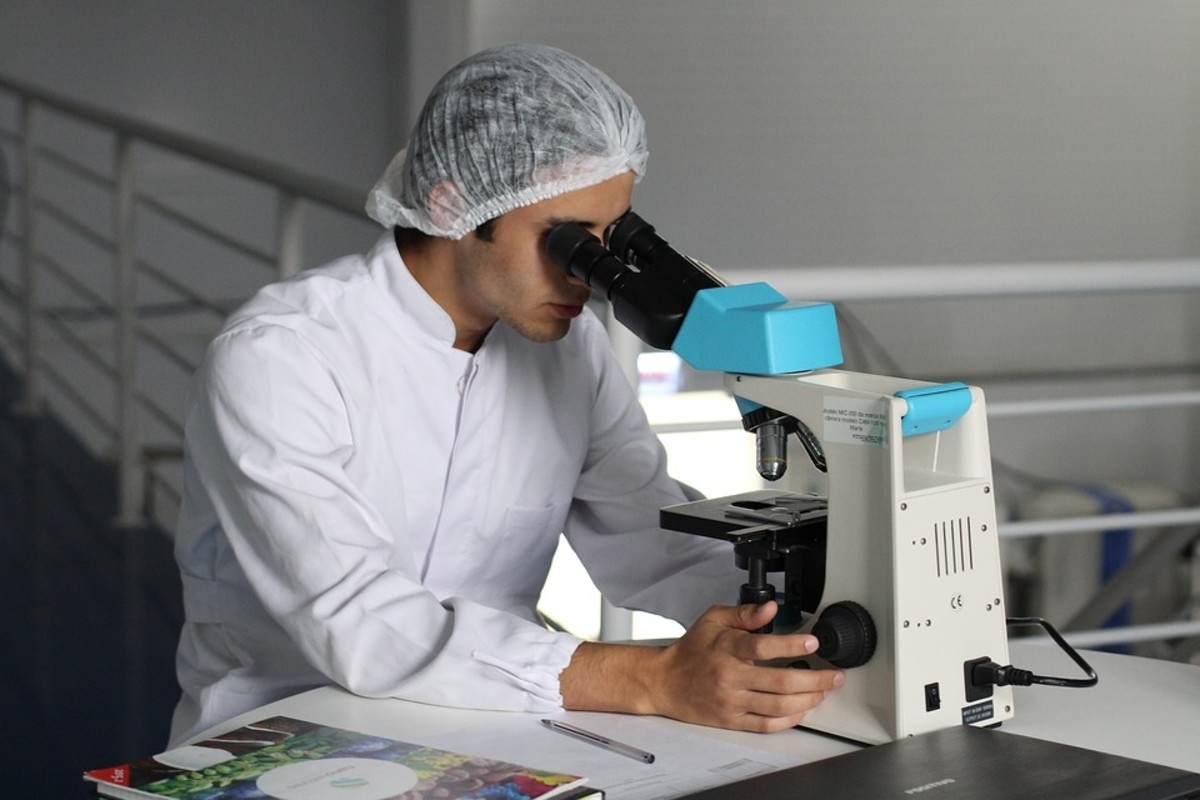 A scientist examines something really small using a microscope.