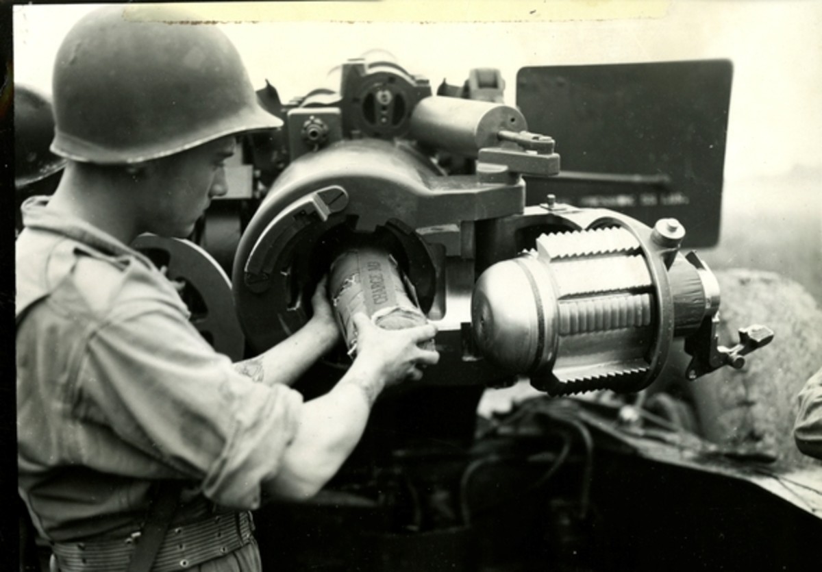 Great close-up of a crewman adding a propellant charge to a 155mm howitzer. 