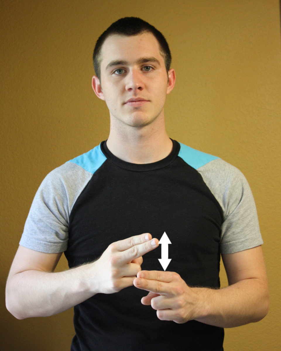Both hands have the index and middle fingers extended. One hand's fingers tap the top of the other hand's fingers.