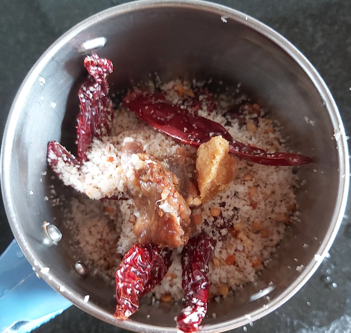 After cooling down, add this mixture to the mixer jar. Add soaked tamarind (no need to add water in which tamarind is soaked) and 1 teaspoon of jaggery.