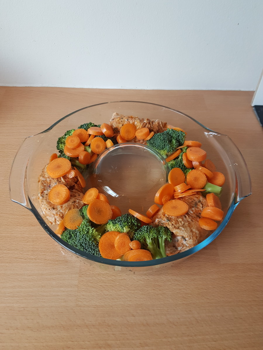 A mix of chicken, carrot and broccoli in a baking dish, ready for the pepper cheese sauce.