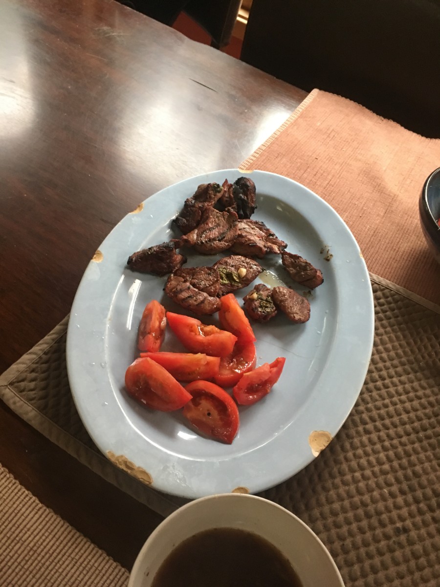 The meat alongside some tomatoes from a tomato salad. 