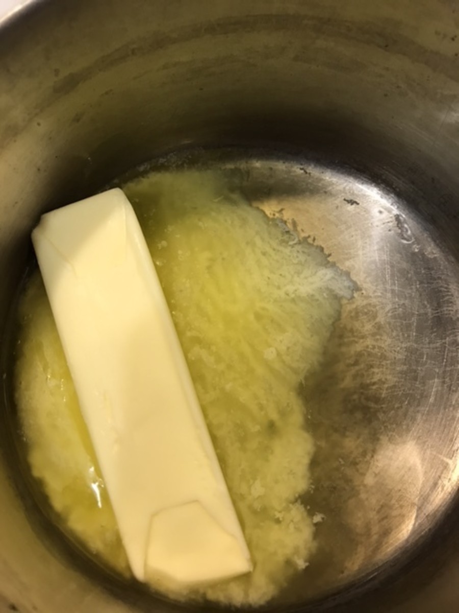Start by melting a stick of butter (1/2 cup) over low heat. Meanwhile, zest 3 tablespoons worth of lemon zest (about three lemons).