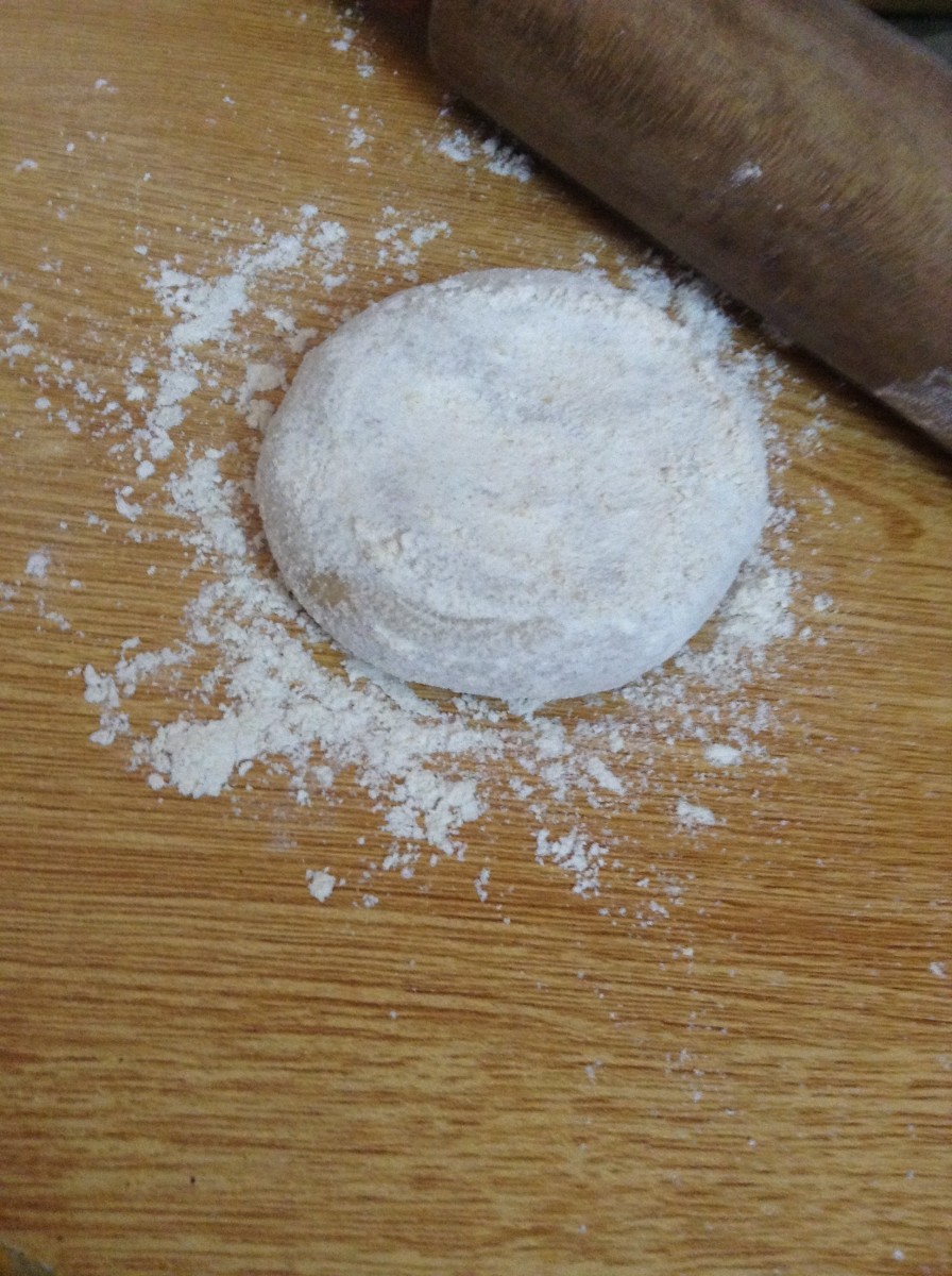 Cover the ball of dough with dry flour while flattening it. This will prevent it from sticking to the wooden board.
