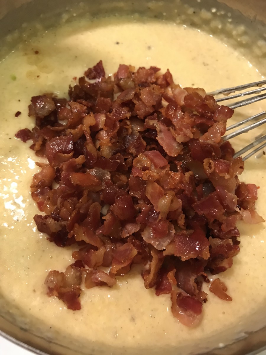 Add the cooked, crispy bacon to the cheesy grits and stir well.