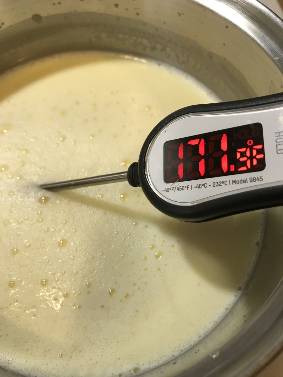 Whisk pretty frequently - milk and cream - especially combined with sugar - will scorch very easily. Whisking helps prevent this, as well as keeping the temperature consistent throughout the mixture. A simple candy thermometer will do the trick.