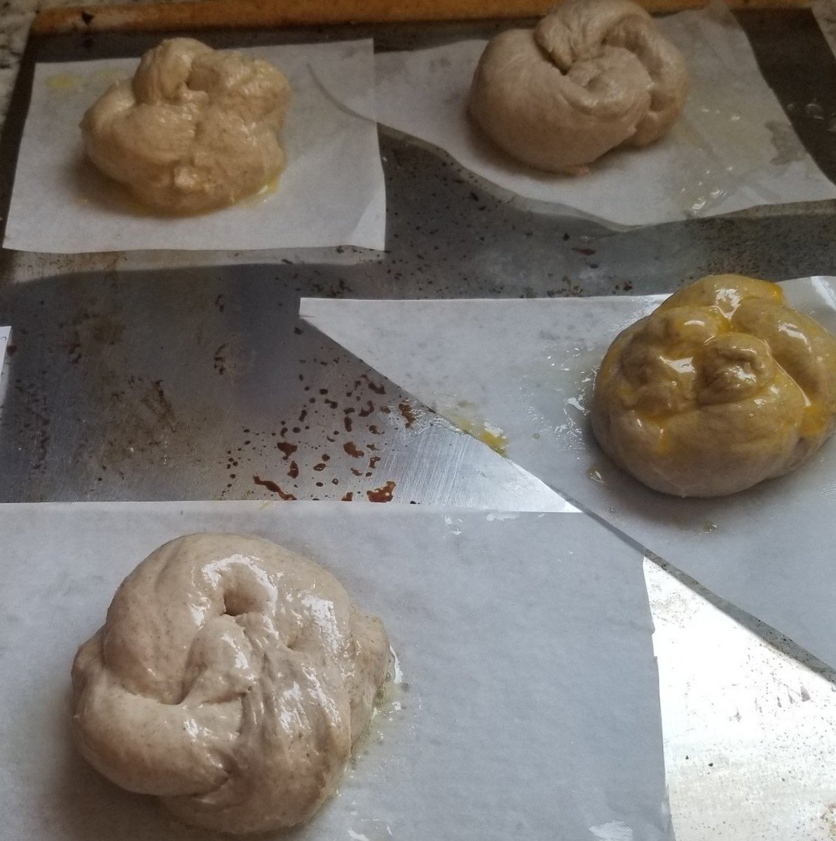 Here are my unbaked, glazed rolls.  The front roll is glazed with butter, and an egg yolk glazes the one on the triangle. There is a water spray on the roll behind it, and the roll on the square is brushed with eggwash.
