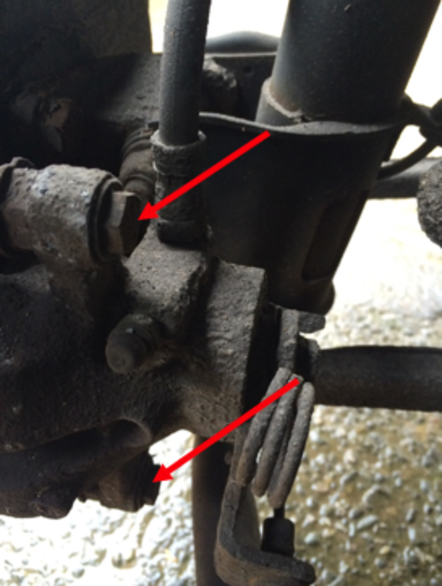 The indicated bolts are removed so the caliper can be freed from its mount.