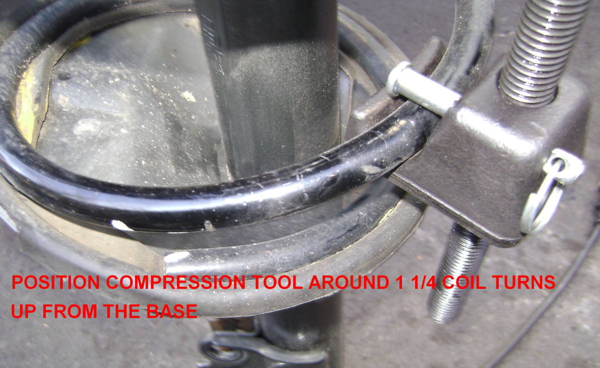 Position the spring compressor about one and one-fourth coil turns up from the base.