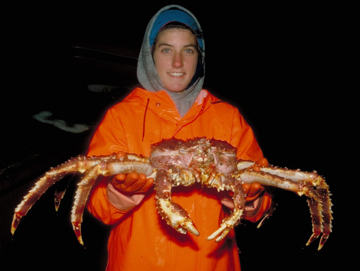 Worker holding a king crab. Men and women both work aboard crabbing vessels and other commercial fishing ships. 