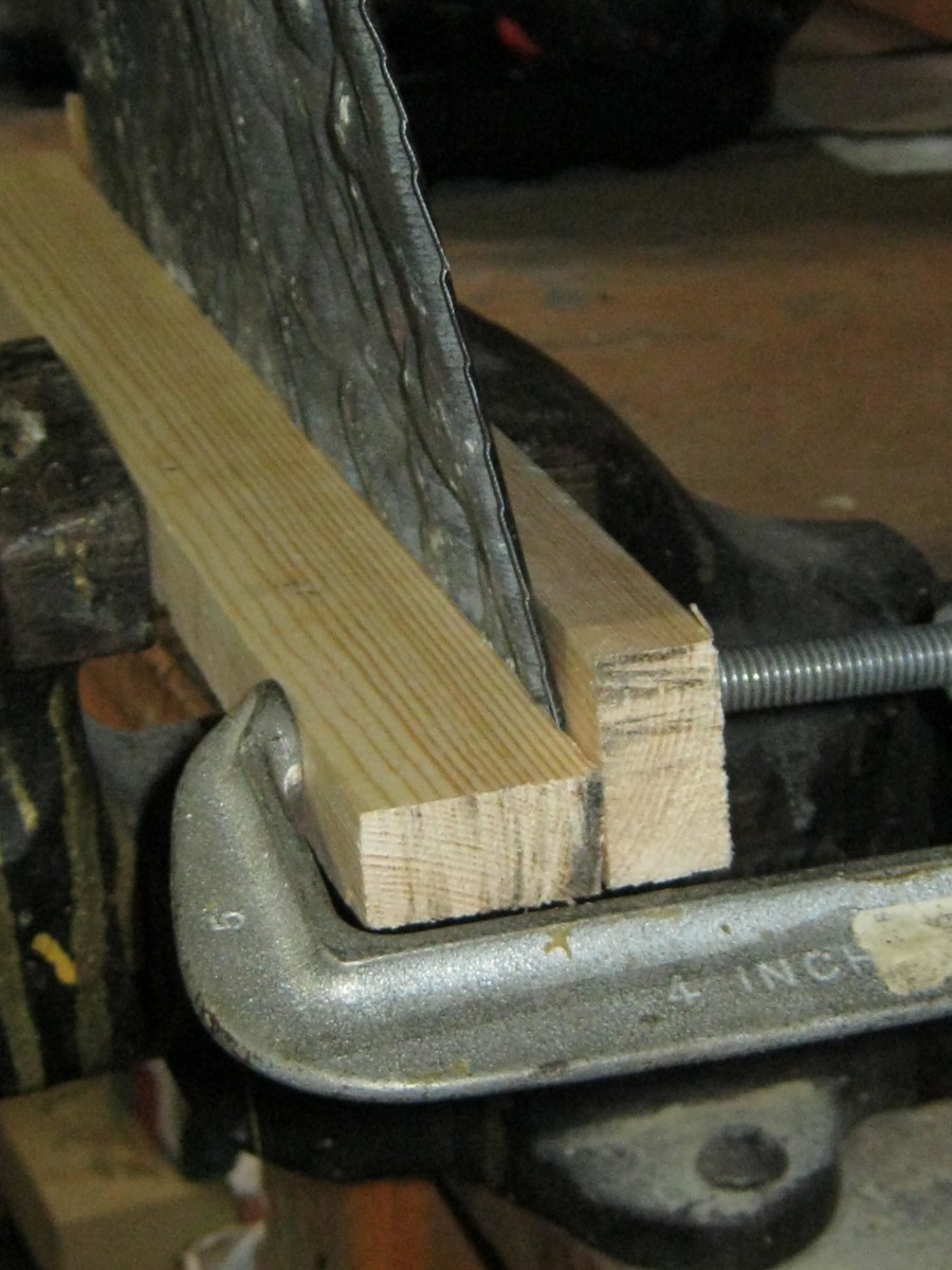 Clamp tin between 2 boards, then between C clamps, then clamp in vise.