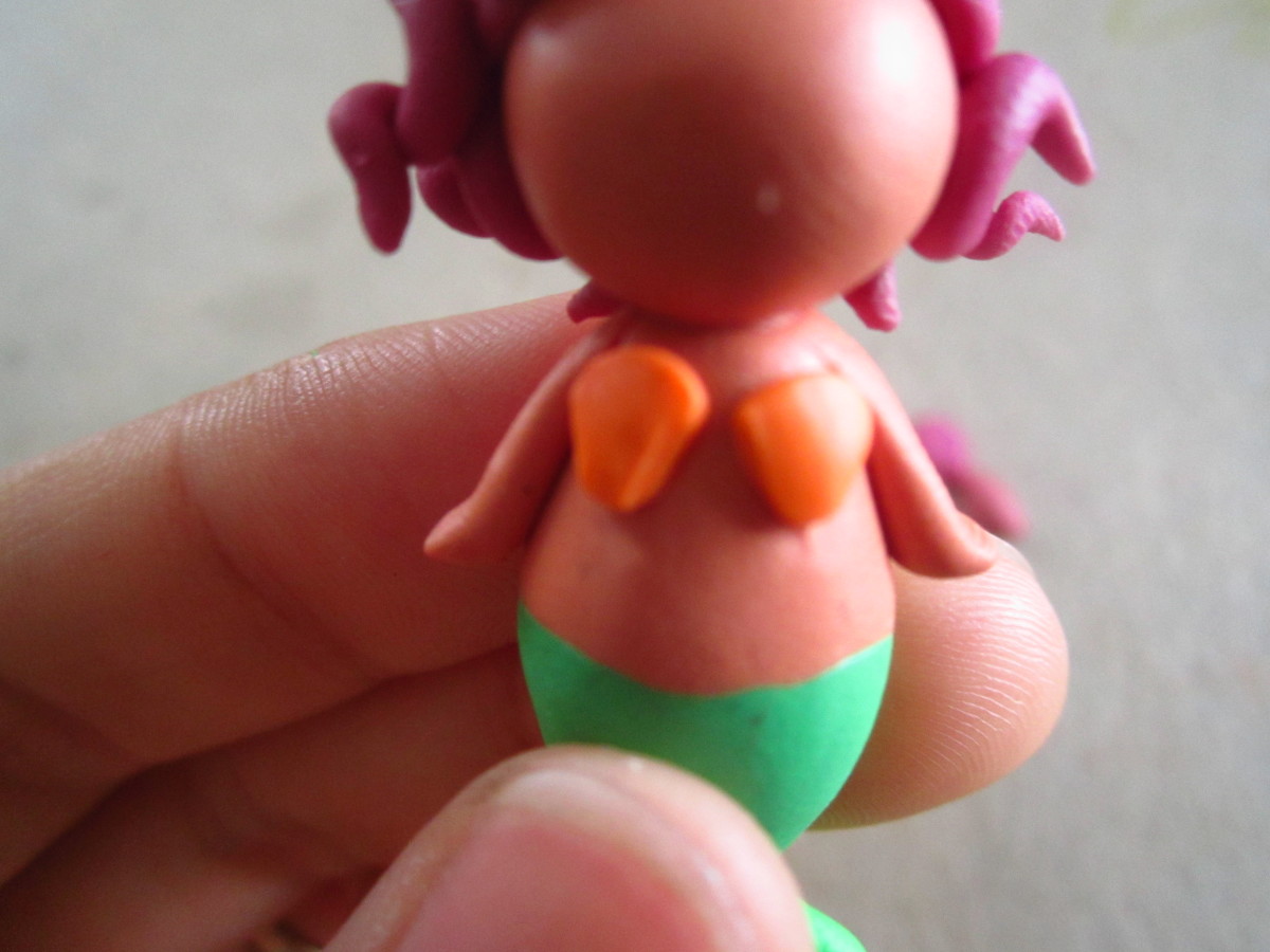 Using your tweezer place and press the tiny balls onto the body of the mermaid.   I then used the back of my tweezer to shape it into more of a shell shape.