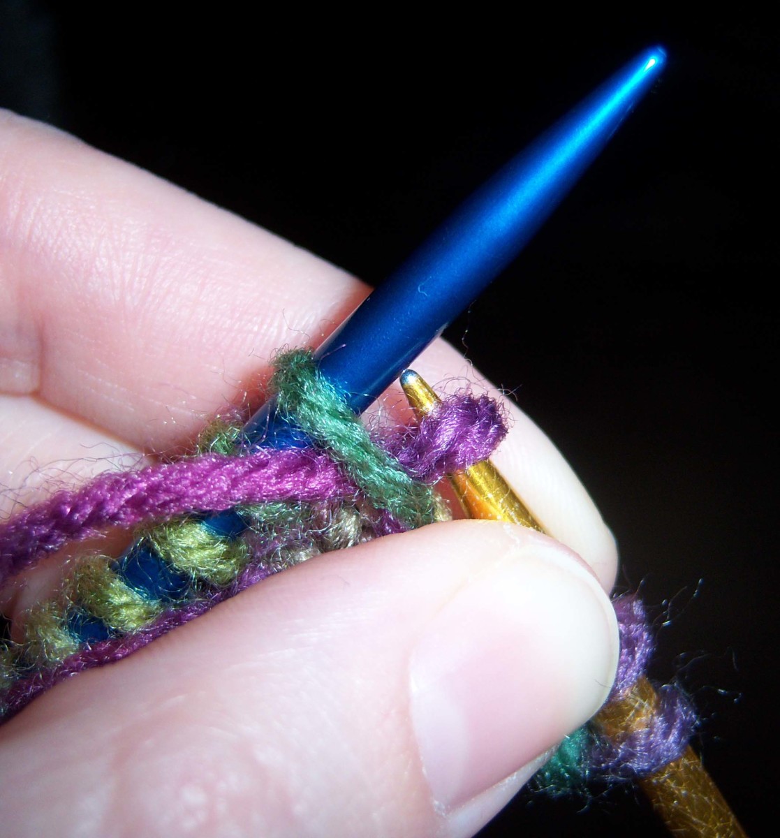 The gold needle is pulled free from the last stitch on the blue one, but not from the looped over yarn.