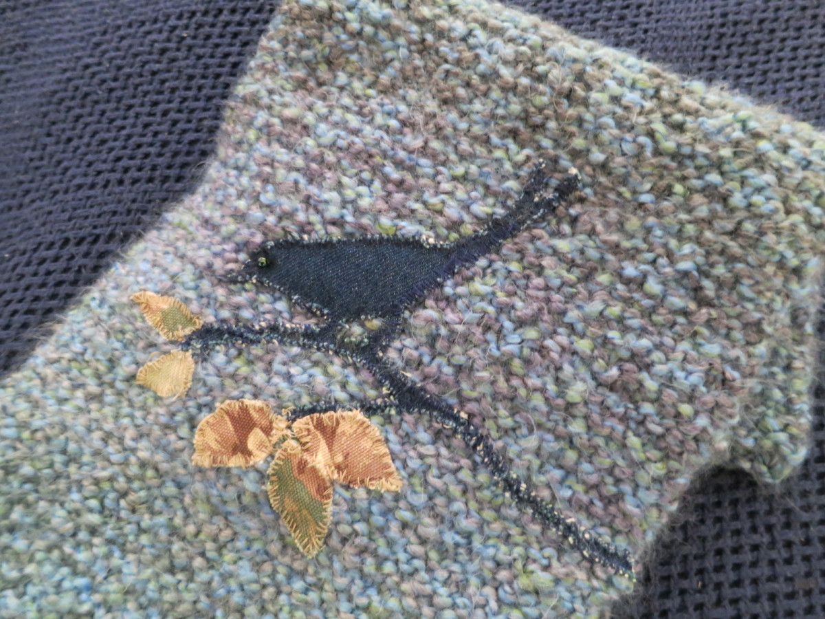 My finished knitting project with appliqued bird and leaves