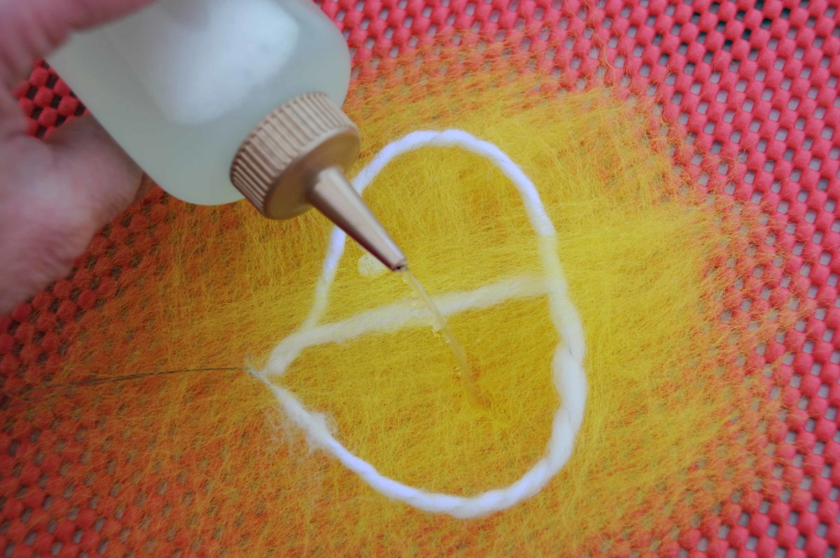 Using the squeeze bottle, wet the wool inside the frame with hot soapy water.