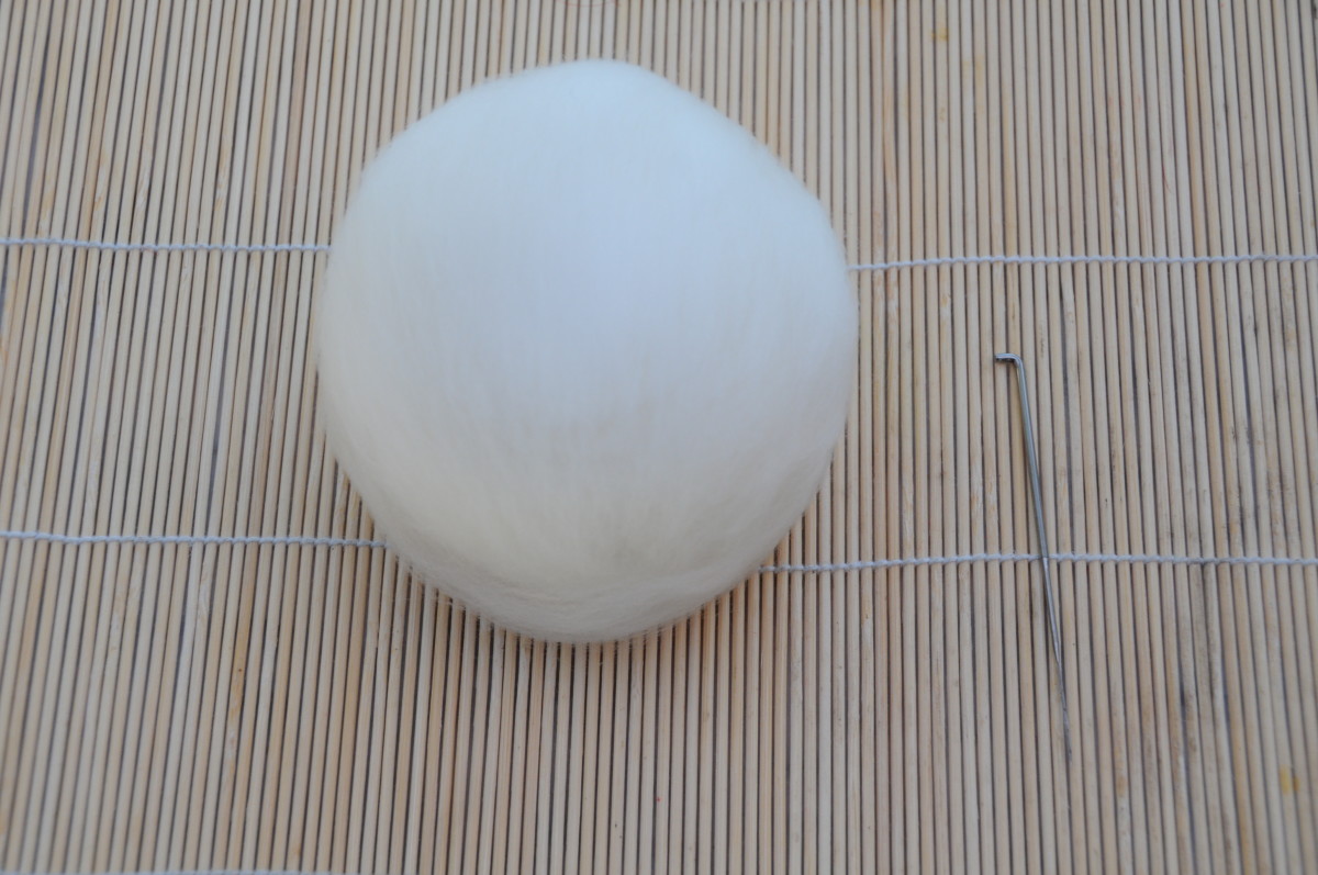 The ball covered in white merino wool roving.