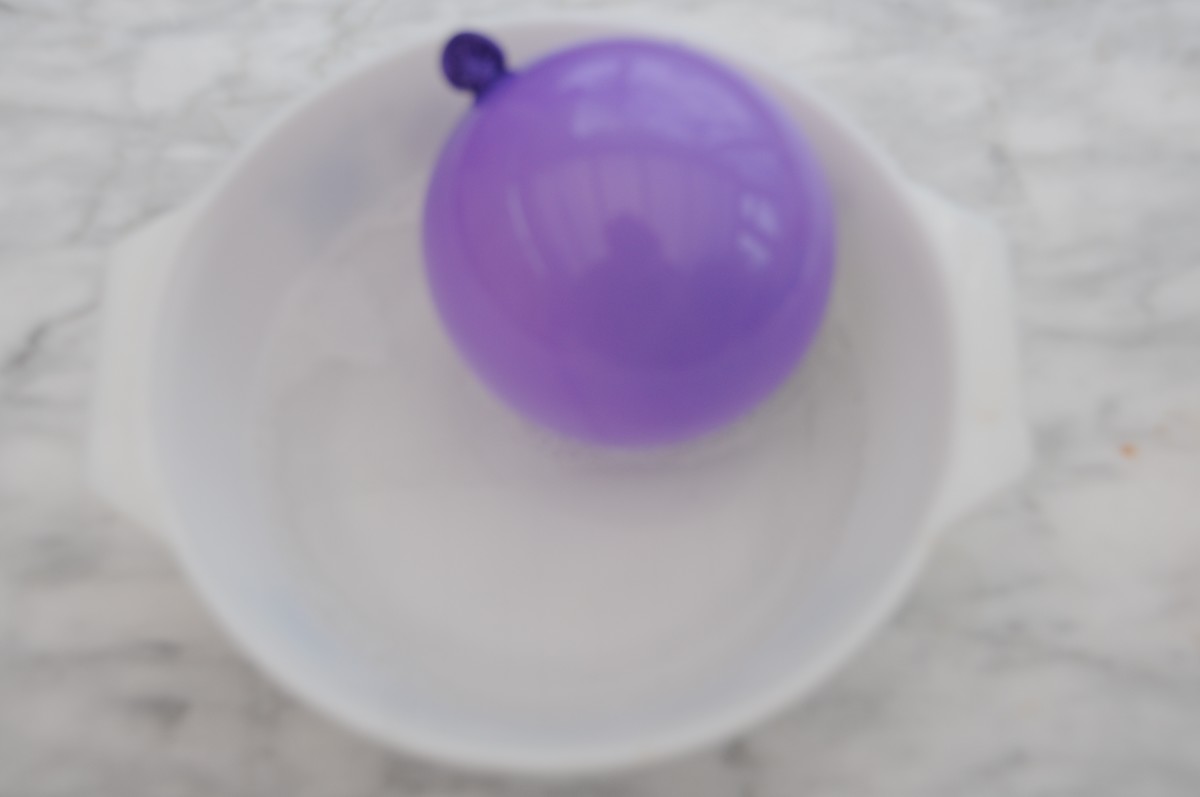 Ball being dipped into warm soapy water - not too hot as balloon will burst.