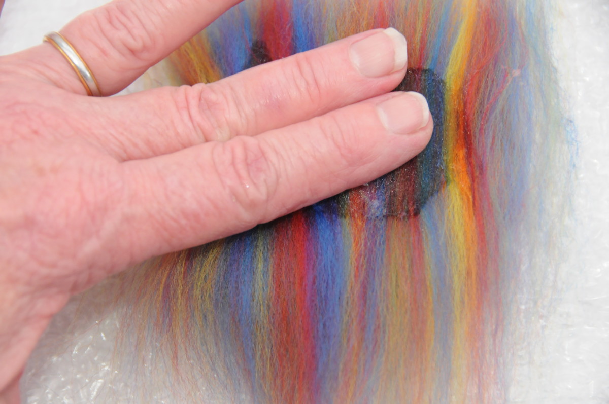 Dampen the woolen fibers carefully with a little hot soapy water.