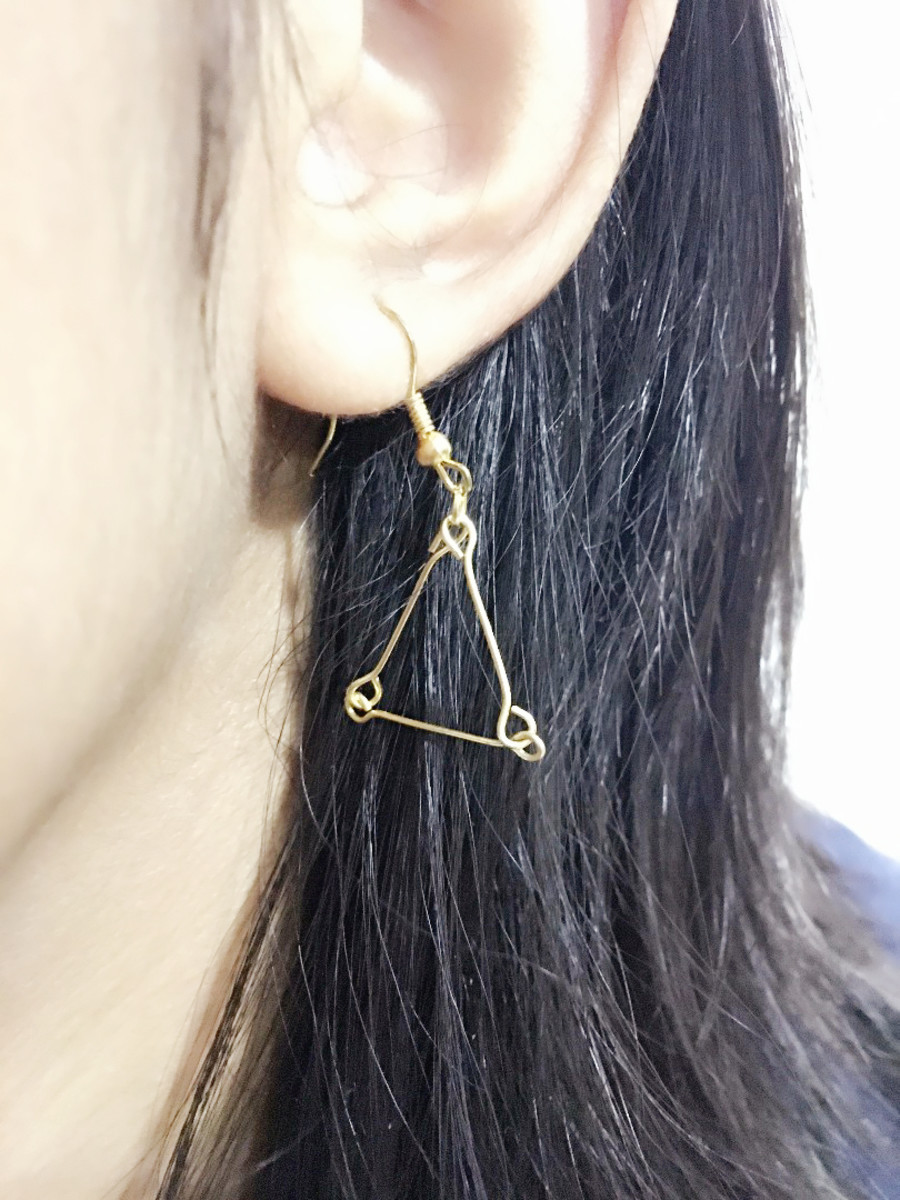 A finished pair of triangle earrings created out of leftover jewelry pieces.