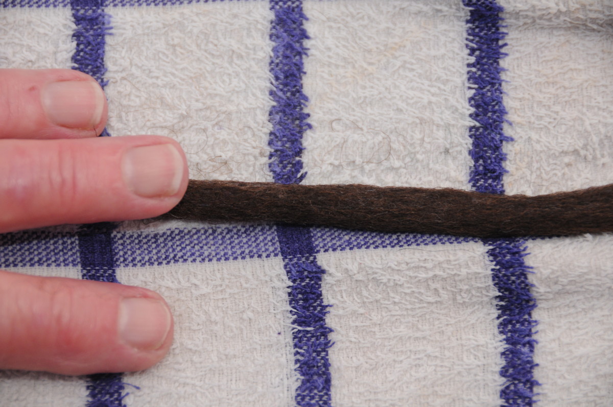 Hold the dreadlock firmly with one hand and rub using your fingers at the angle shown in this image.