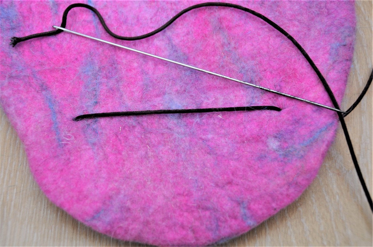Use a large needle to sew from the rear of the hot water bottle cover to the front and through the 2 circles of felt.