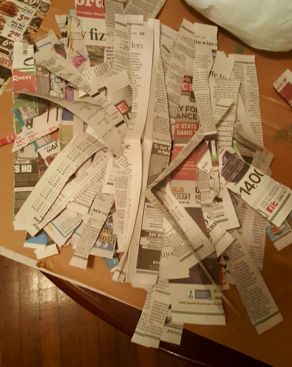 Rip newspaper into strips and gather into a pile.