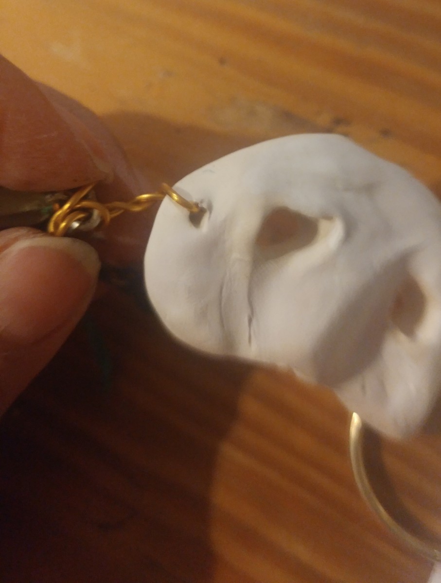 Run wire through the small hole in mask,  and attach to last link of the small chain.