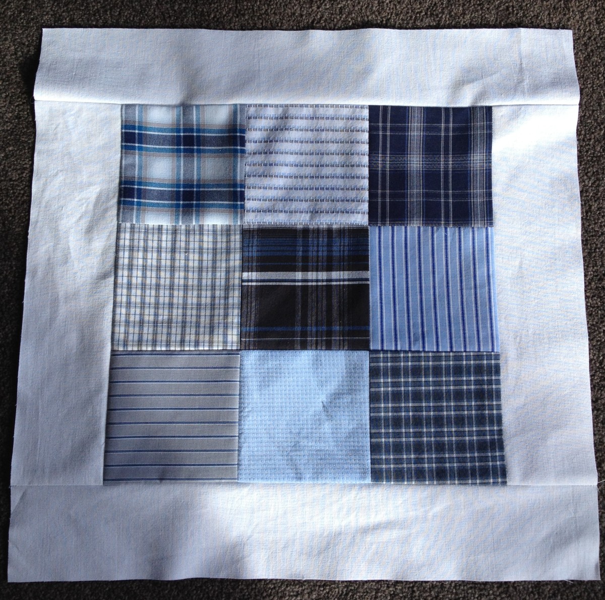 A nine-block square section of an upcycled men's shirt quilt