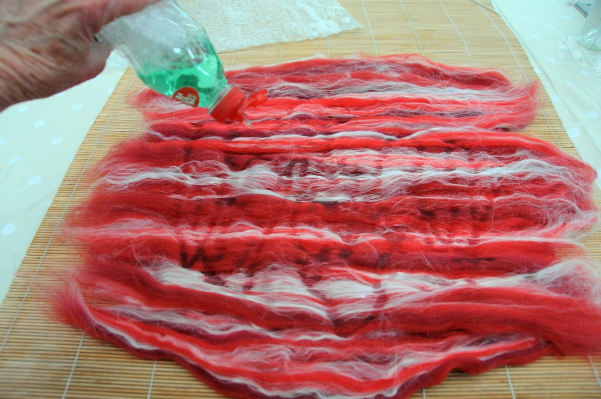 Add hot soapy water to the surface of the opened out wool and silk fibers.