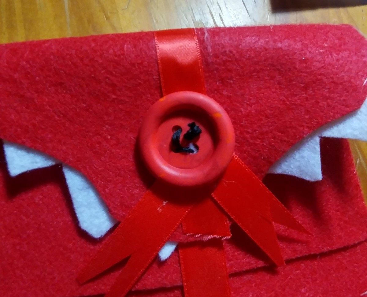 Choose a large red button to give effect. Sew the button onto the front of envelope. I used black yarn, but thread will work just fine.