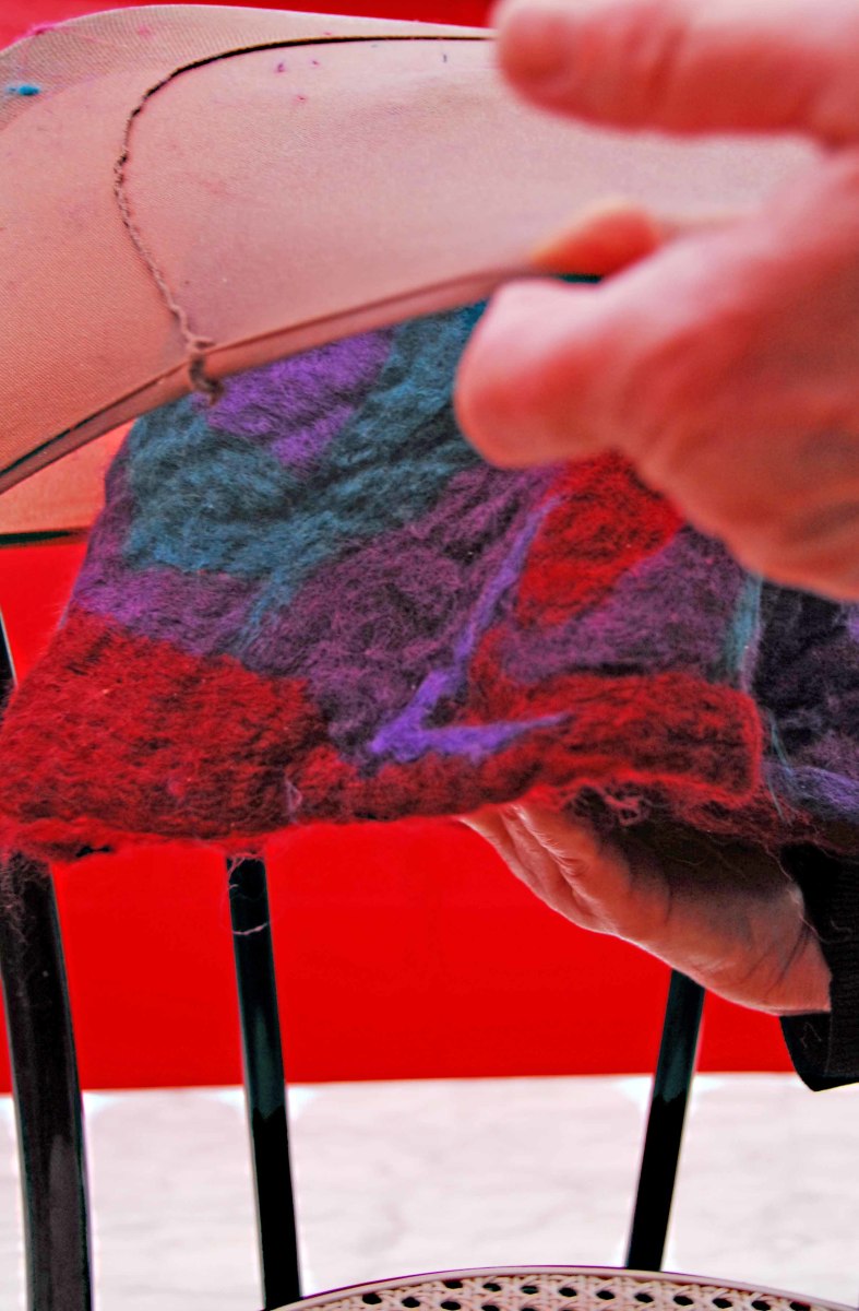Insert the felt-covered ball into the stocking. Use the back of a chair in place of that extra pair of hands if there is not another pair available to help.
