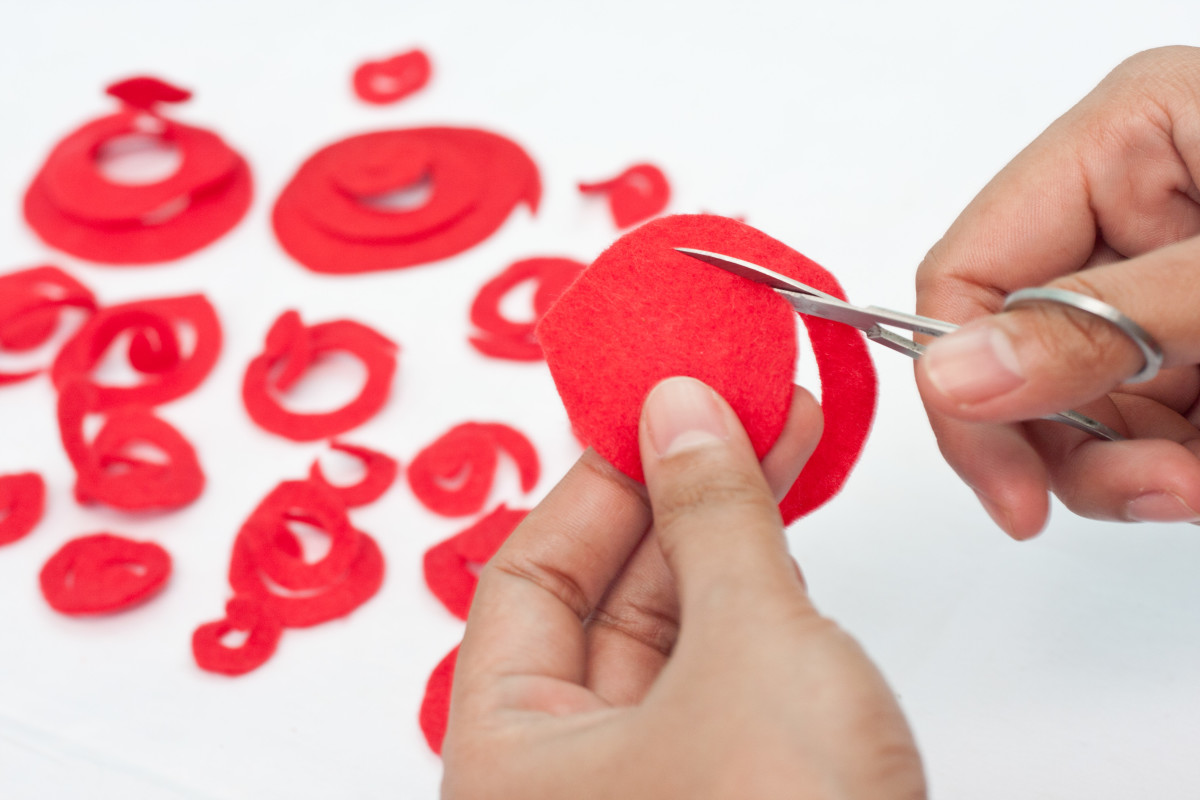 Step 6: Using the smaller scissors, cut each felt circle in a swirling fashion (take a good look at the picture above). Start from the outside and work your way to the center... but make sure not to cut the center... keep the strip intact.