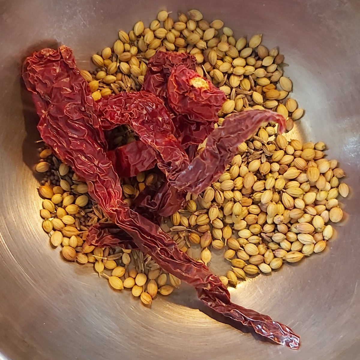 Add 4 to 5 dry red chilies and dry-fry over low heat till the spices turn aromatic (the mustard seeds should splutter, the coriander seeds should turn golden brown and the red chilies should become crisp). Switch off the heat.