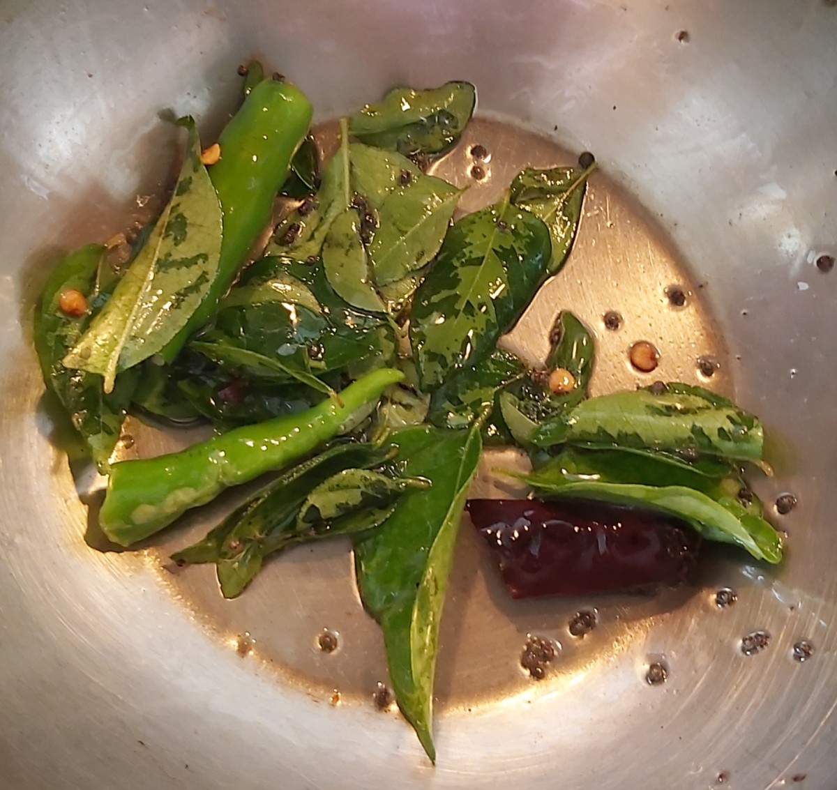 Make the tempering: In a frying pan, heat oil or ghee, splutter the mustard seeds, add broken red chilies, 1 to 2 green chilies and fresh curry leaves. Fry.