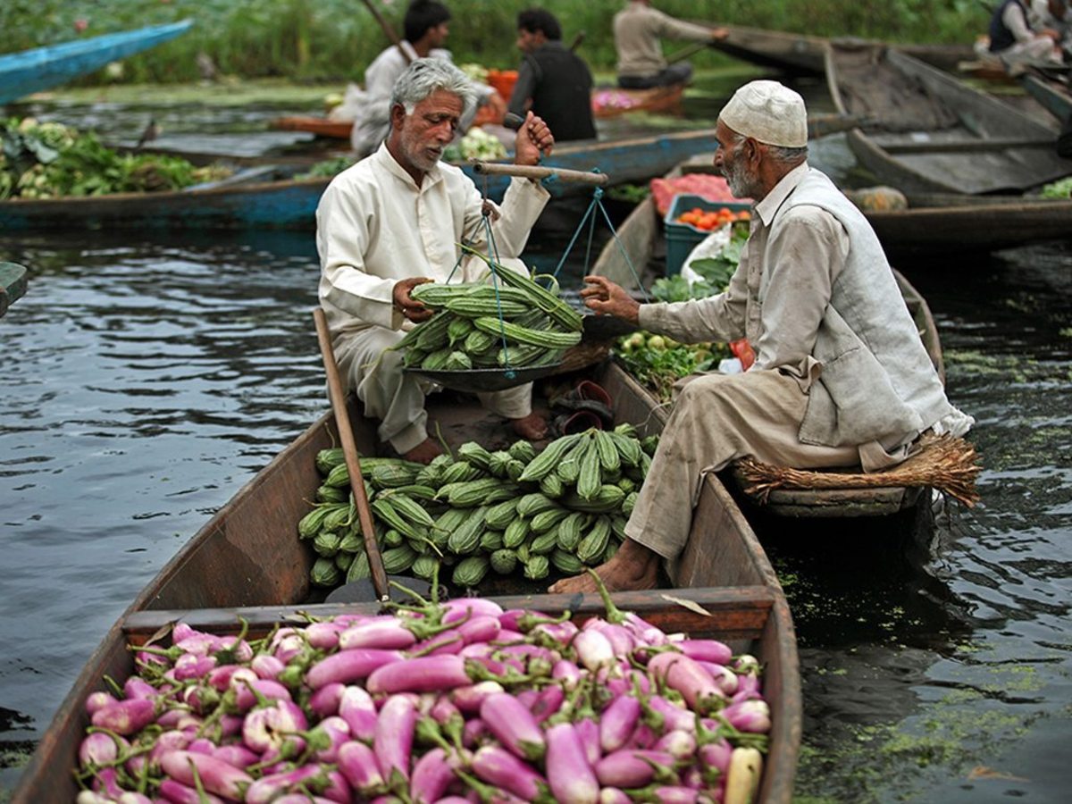A supplier weighs vegetables to sell to a vendor at the floating vegetable-market.