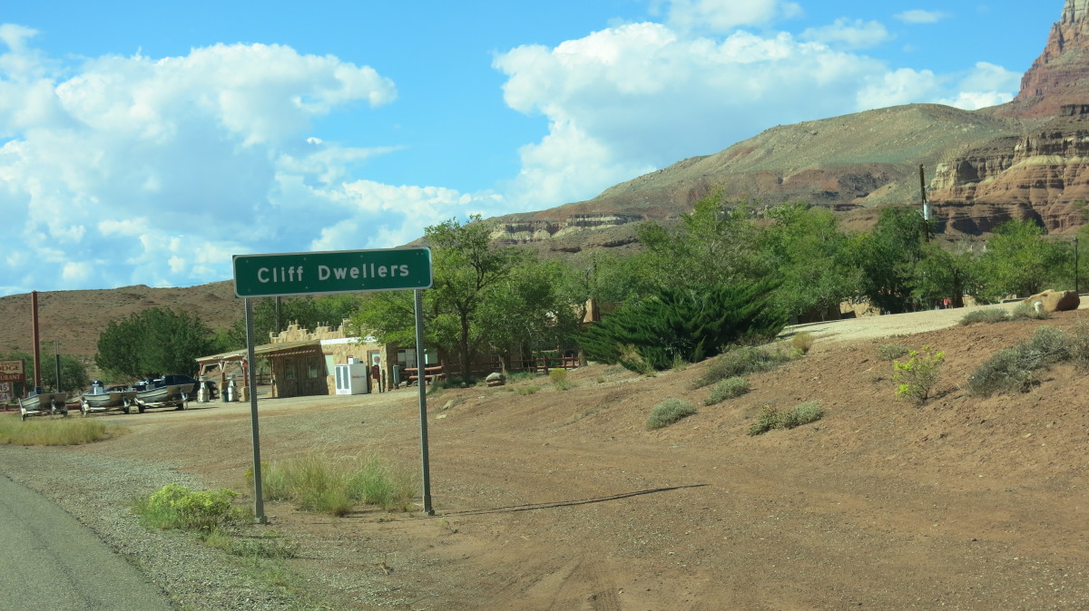 Road sign announcing Cliff Dwellers with gas station in background as you round the bend after passion the field of boulders and original rock structures.