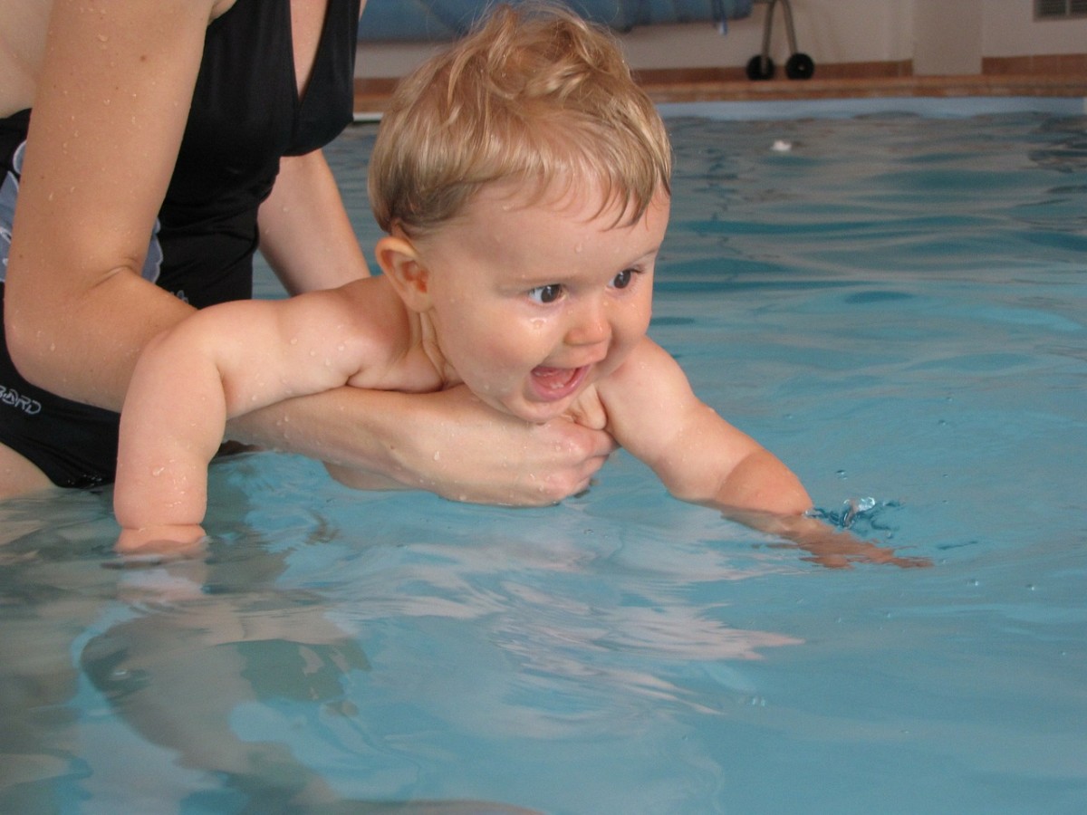 A baby gets a swimming lesson. Some babies enjoy learning to swim.
