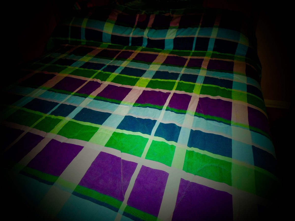 A bed with a green, blue and purple comforter on it.