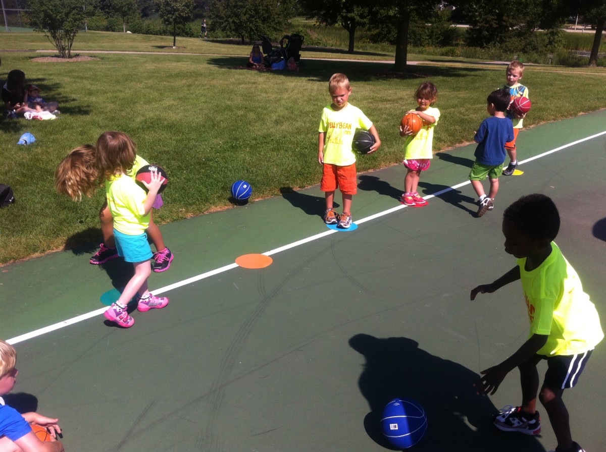 Young children practice dribbling a basketball
