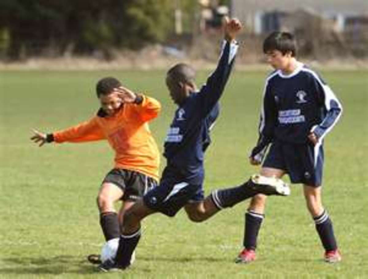 The defender in orange is about to block the shot. The block tackle is aimed at disrupting the opponent's attack or play.